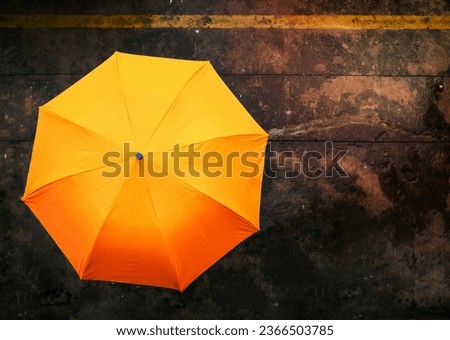 An orange umbrella on rainy day on wet congrete background .Top view