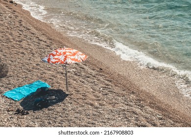 Orange Umbrella Placed On The Shore Of The Beach.