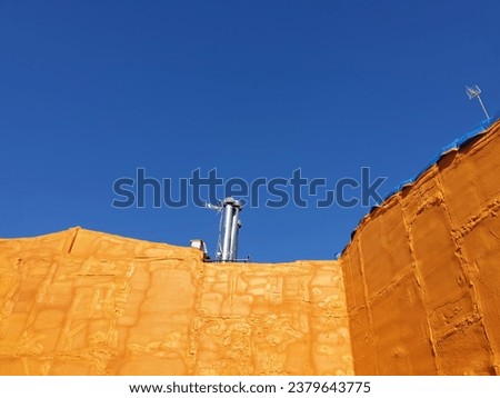 Orange urethane foam on the building, orange wall with blue sky in Spain