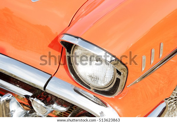 Orange vintage car on a festival of old cars. Retro\
car\'s headlight close\
up.