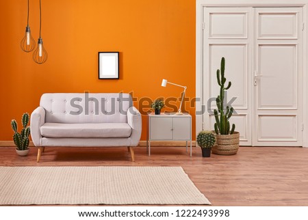 Orange wall and grey sofa with white classic door background. Modern orange lamp with vase of plant interior room.