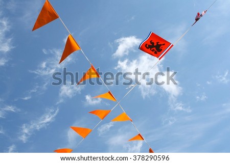 Orange waving flags with national Dutch lion in a blue sky, Netherlands.  Local culture at national holidays and Fifa World Championship Football in Qatar