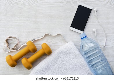 Orange Weights, Phone, Headphones, Measure Tape, Bottle Of Water And Towel On Wooden Table. Fitness, Sport Time, Flatlay