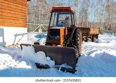 Orange Wheeled Snow Plow Tractor With Blade In Winter