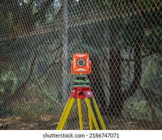 An orange and white transit level sits atop a yellow and red tripod at Lake Hollywood in Los Angeles, CA.