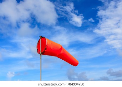 Orange Wind Sock In Blue Sky And White Cloud Background.