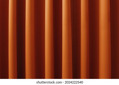 Orange window curtain fabric that forms an orderly composition of waves.
