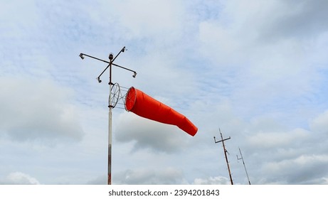 orange windsock with cloudy sky view close up - Shutterstock ID 2394201843