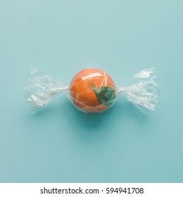 Orange wrapped like candy on bright blue background. minimal food concept.