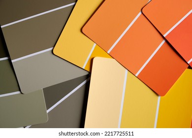 Orange yellow and green color swatches scattered on a table. Generic color swatches are in various autumnal shades of yellows, oranges and greens. Fall color schemes. Interior design inspiration