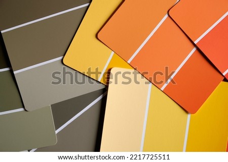 Orange yellow and green color swatches scattered on a table. Generic color swatches are in various autumnal shades of yellows, oranges and greens. Fall color schemes. Interior design inspiration