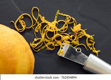 Orange Zest And Zester, Top View, On Dark Slate.  With Whole Fruit.