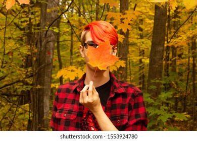 An orange-haired young man's face is obcured by an orange maple leaf.