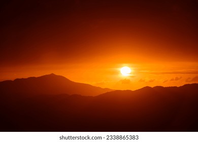 The orange-red sunset is covered by clouds as it moves towards the horizon. View of the urban landscape from Dajianshan Mountain, New Taipei City.