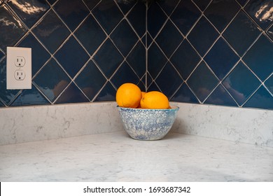 Oranges In A Blue And White Bowl On A Granite Counter With A Blue Tile Backsplash