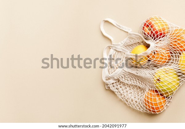 Oranges\
in mesh bag with design space on beige\
background