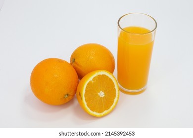 Oranges Next To A Glass Filled With Orange Juice On A White Background, Overhead View