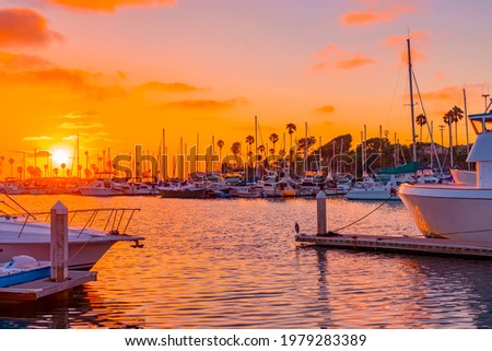 Oranges and pinks highlight all the boats,  rippled water and sky in Oceanside Harbor, near Carlsbad, California in Southern California.