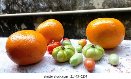 Oranges and tomatoes are placed on a cement bench. High angle view. Fresh fruits.