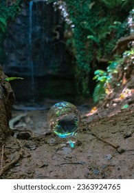 Orb with colours in front of waterfall 