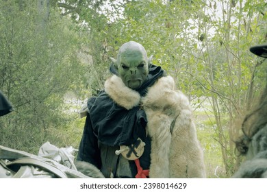 An orc character from a LARP (Live Action Role Play) staring at some daring adventurers. Fantasy setting.
