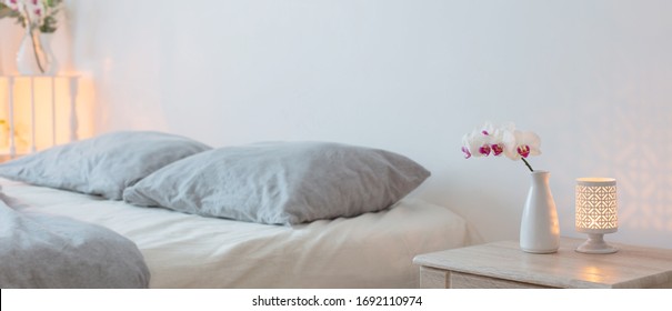 orched flowers  in vase and burning candles in white bedroom