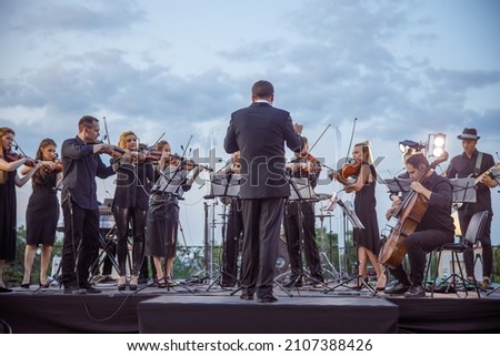 Orchestra playing classic instrumental music under cloudy sky