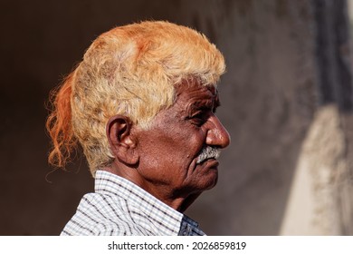 Orchha, Madhya Pradesh, India - March 2019: Candid Side Profile Portrait Of An Elderly Indian Man With Orange Dyed Hair.