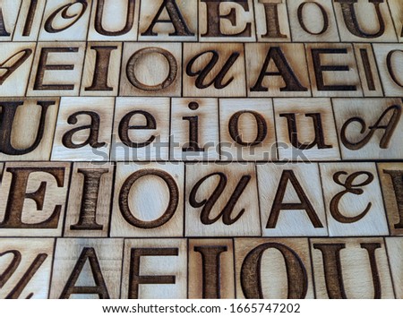 ordered vowels capital and lowercase engraved on pieces of wood