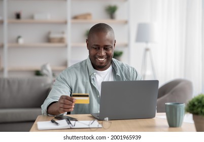 Ordering Services Online, Buying And Paying With Money From Banking, Shopaholic. Happy Middle Aged African American Male Disabled Looking At Laptop And Credit Card In Living Room Interior, Copy Space