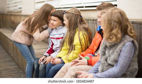 Ordinary Children On A Bench Playing Chinese Whispers