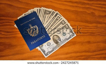 An ordinary Cuban passport with several dollar bills, on a wooden table. Travel photography