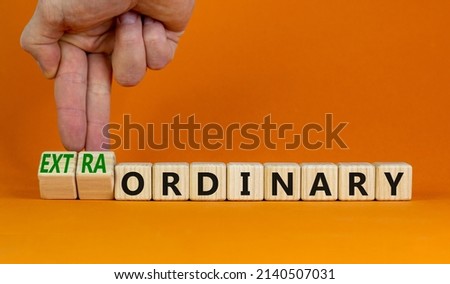 Ordinary or extraordinary symbol. Businessman turnes wooden cubes and changes words 'Ordinary extraordinary'. Beautiful orange background. Business, ordinary or extraordinary concept. Copy space.
