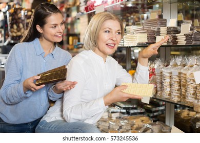 Ordinary female customers selecting delicious milk chocolate in shelf