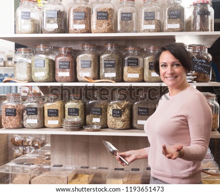 ordinary woman buyer selects herbs in store of ecological products