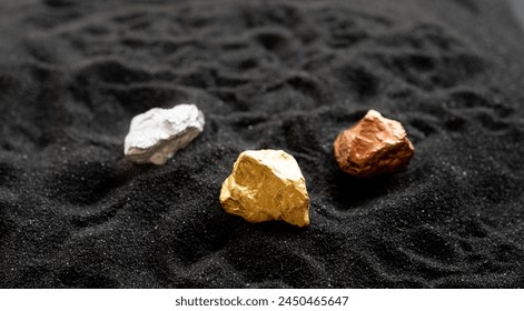 L'argent et le cuivre de l'or provenant des mines ont été placés sur le sable noir. : photo de stock