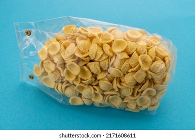 Orecchiette pasta in transparent sealed package for sale on blue background, Italian pasta from Puglia made with durum wheat flour and water, typical of the Apulian cuisine