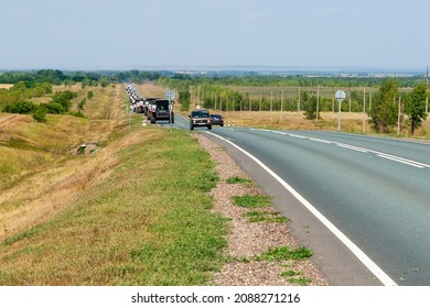 Orenburg Region, Russia, 07.30.2021 A Large Column Of Combines Is Walking Along The Highway. Relocation Of Agricultural Machinery.