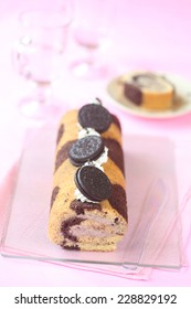 Oreo Swiss Roll Cake With White Chocolate And Cream Cheese Filling On Light Pink Background.