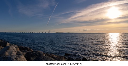 The Oresund Bridge (Öresundsbron) And Copenhagen In The Distance, While The Sun Sets Over The Oresund Sound (Öresund) Outside Malmö, Skåne, Sweden.