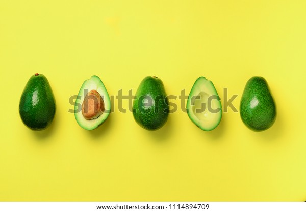 黄色い背景に有機アボカドと種子 アボカドの半分とフルーツ 平面図 ポップアートデザイン クリエイティブな夏の食べ物のコンセプト 最小限の平らなレイの緑の アボカドの柄 の写真素材 今すぐ編集