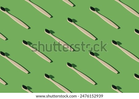 Organic bamboo toothbrush pattern composition on green background. Minimal dental concept. Creative eco friendly, biodegradable and natural wooden toothbrush pattern background idea.