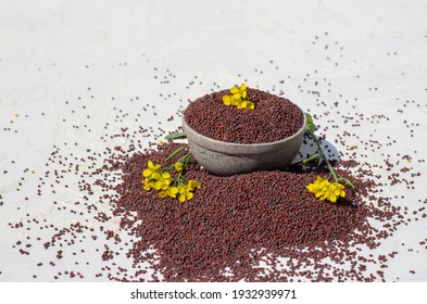 Organic Black Mustard Seed In Stone Bowl With Yellow Mustard Flower Isolated White Background