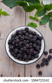 Organic Black raspberry in a white enamel plate on a gray wooden background