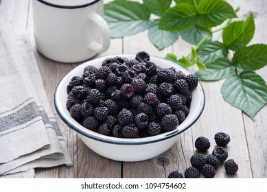 Organic Black raspberry in a white enamel plate on a gray wooden background