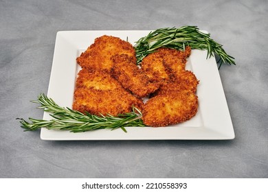 Organic Breaded Chicken Cutlet Served On A Plate With Rosemary Garnish