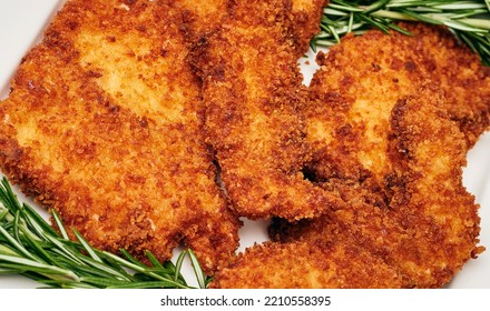 Organic Breaded Chicken Cutlet Served On A Plate With Rosemary Garnish