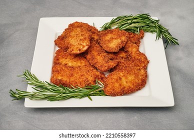 Organic Breaded Chicken Cutlet Served On A Plate With Rosemary Garnish