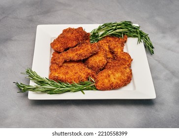 Organic Breaded Chicken Cutlet Served On A Plate With Rosemary Garnish