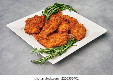 Organic Breaded Chicken Cutlet Served On A Plate With Rosemary Garnish